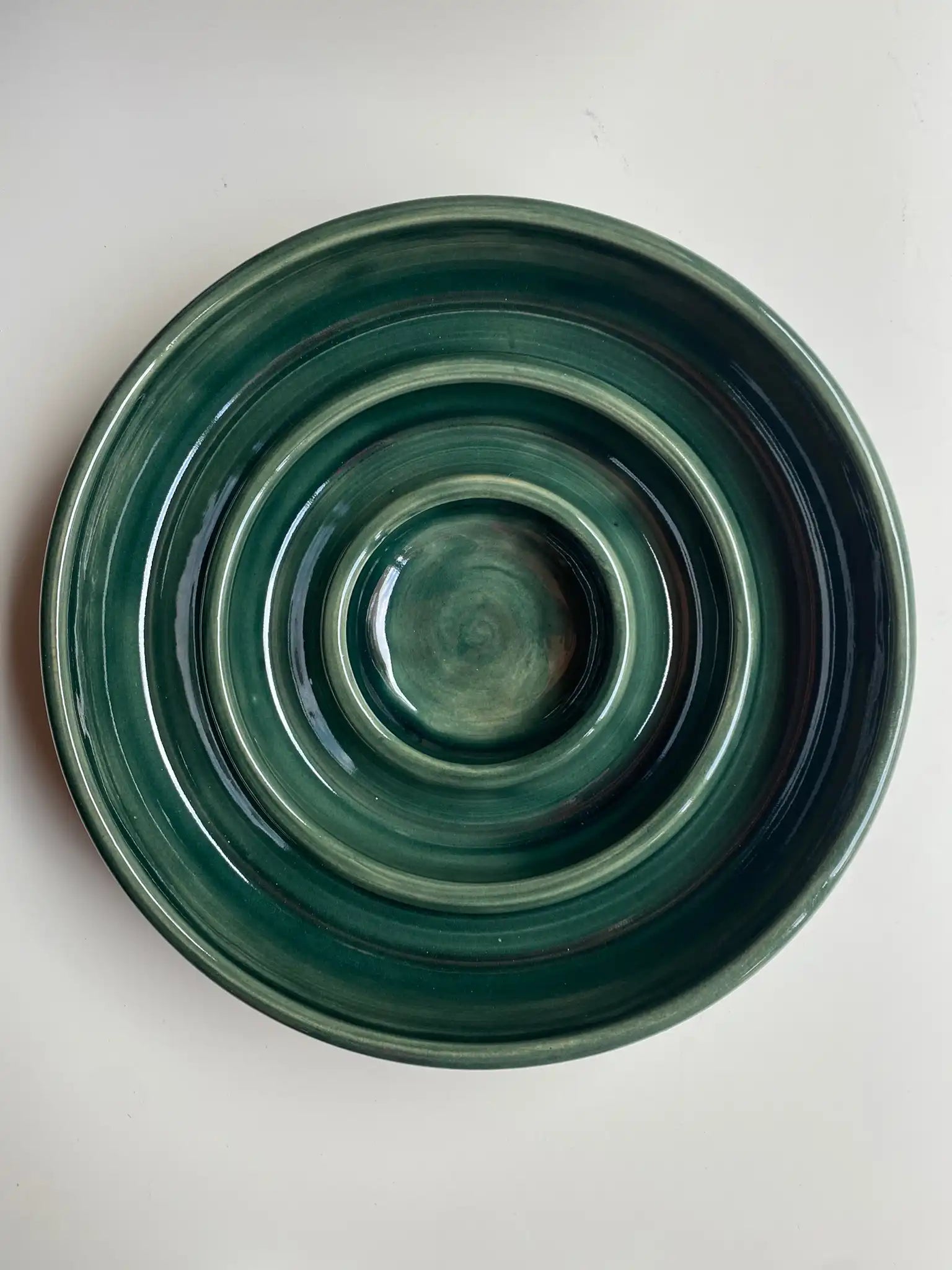 Handgemaakte keramieken slowfeeder  van Iris Floor in glanzend mosgroen. De voerbak is speciaal ontworpen met ringen om schrokken bij honden te voorkomen.