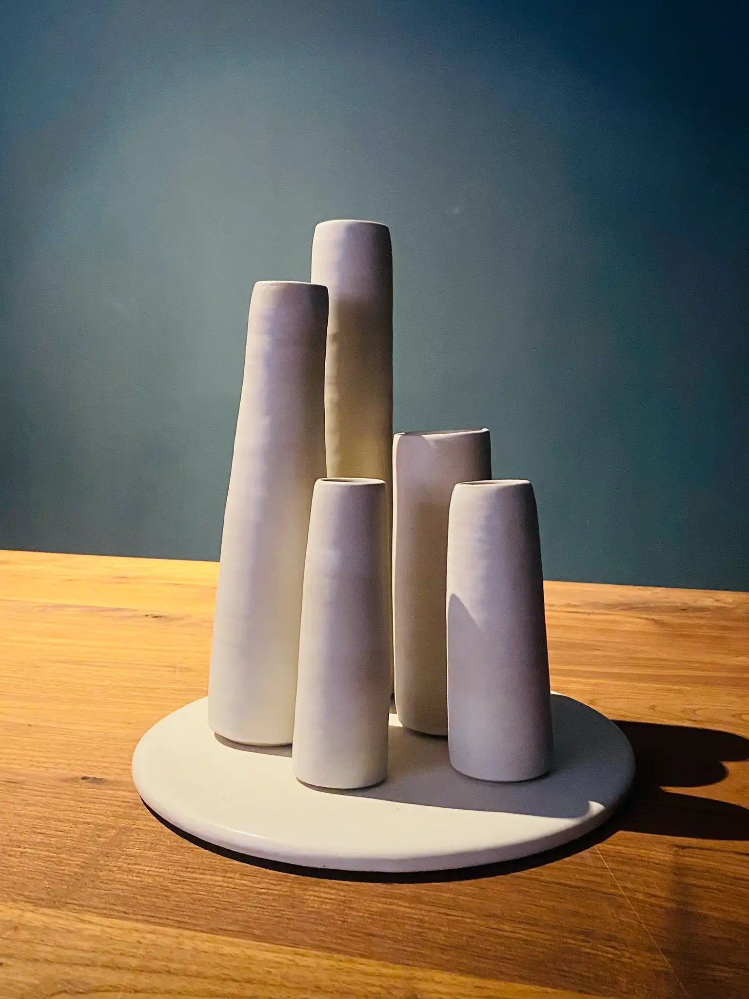 Handgemaakte keramieken vazen set van Iris Floor. Vijf minimalistische, matwitte vazen in verschillende hoogtes op een ronde tray.