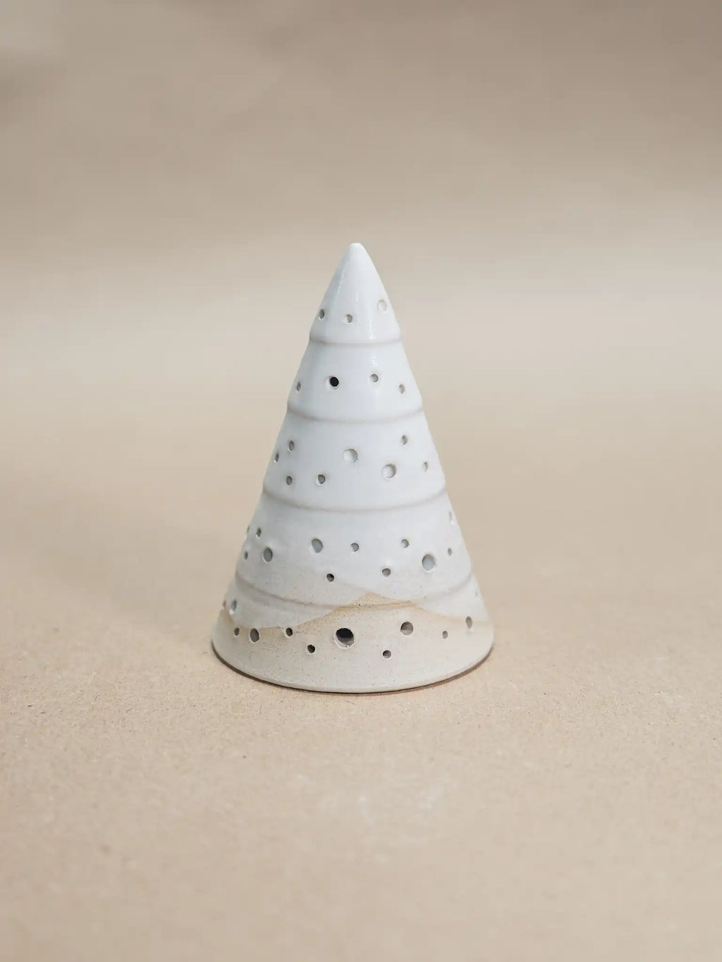 Medium handgemaakt keramiek kerstboompje met uitgestoken gaatjes voor waxinelichtje in mat wit glazuur, op beige achtergrond — Iris Floor Ceramics