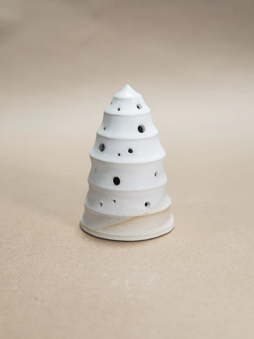 Medium handgemaakt keramiek kerstboompje met uitgestoken gaatjes voor waxinelichtje in mat wit glazuur, op beige achtergrond — Iris Floor Ceramics