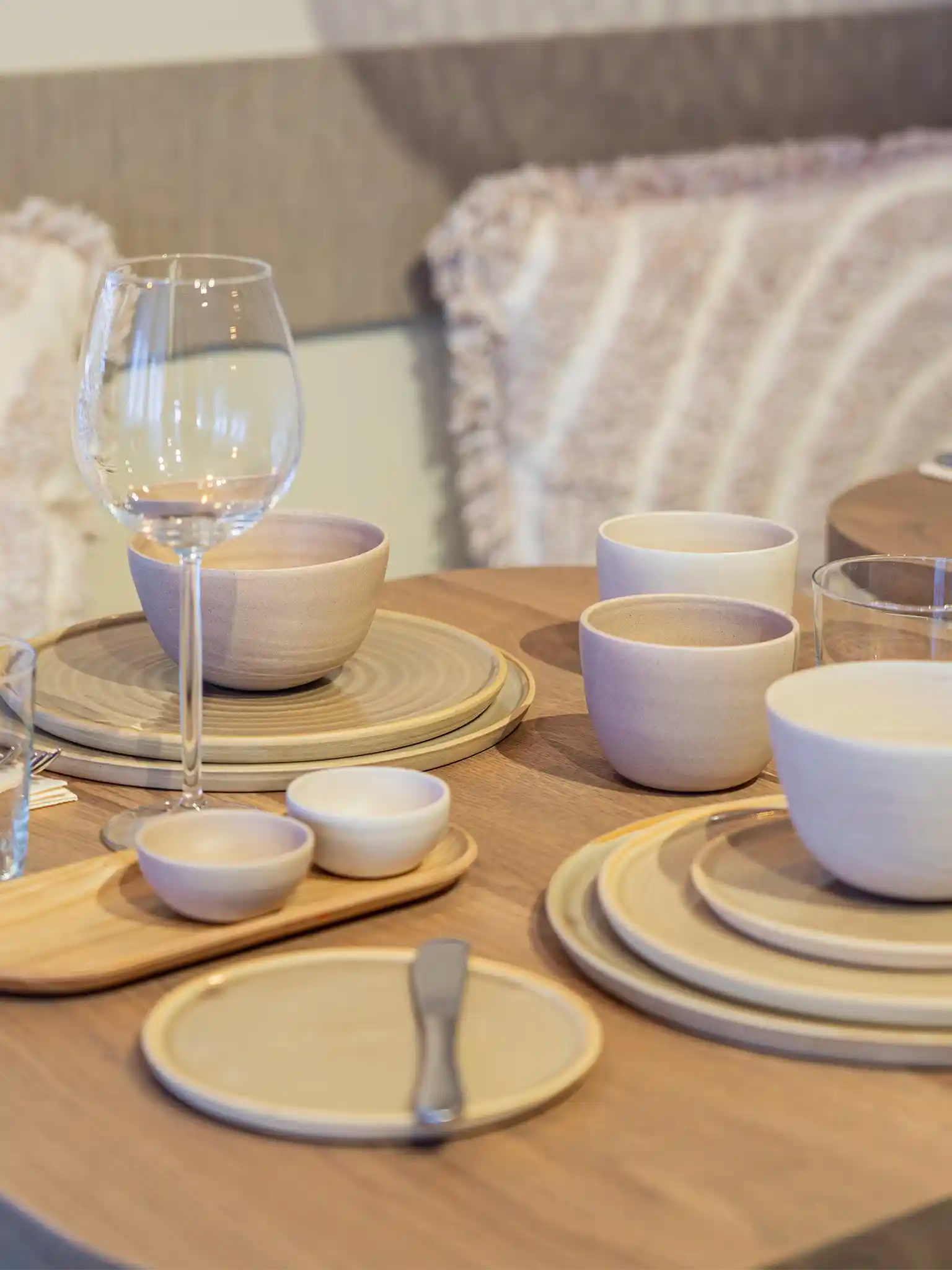 Gedekte eettafel met handgemaakte keramieken borden, kommen en bekers in lila en zandtinten, gecombineerd met wijnglazen en bestek — Iris Floor Ceramics